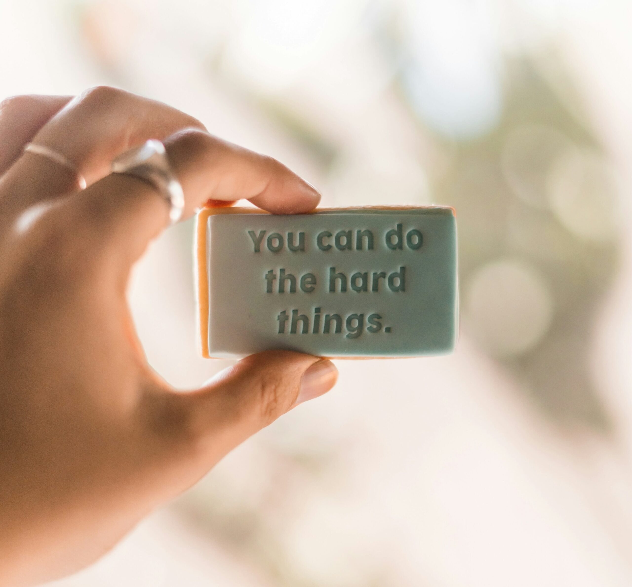 Hand holding a sign that says you can do the hard things
