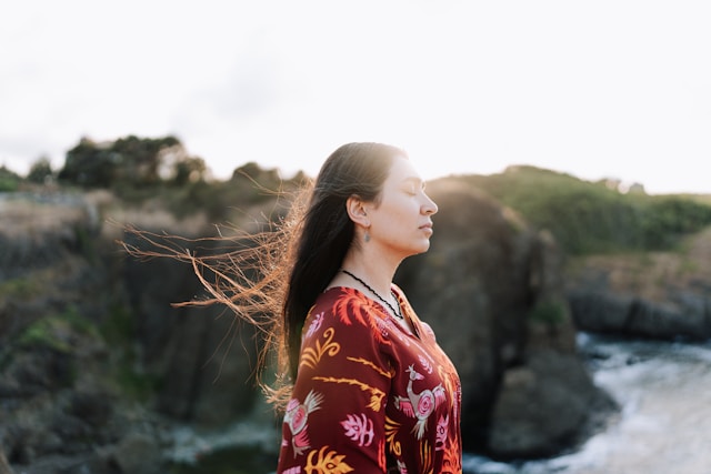 Woman breathing outdoors with wind blowing her hair in sunlight (Ahmed for unpsplash)