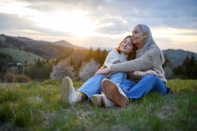 Grandmother and granddaughter sitting in the grass (Unsplash)