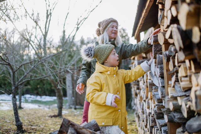 Grandparent with grandchild stacking wood (Unsplash)