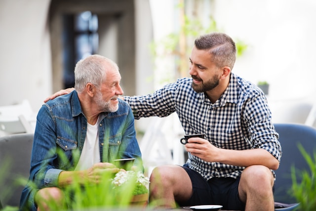 Younger man and older man having coffee (Unsplash)