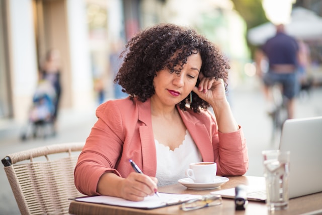 Woman having coffee and writing (Unsplash/Getty)