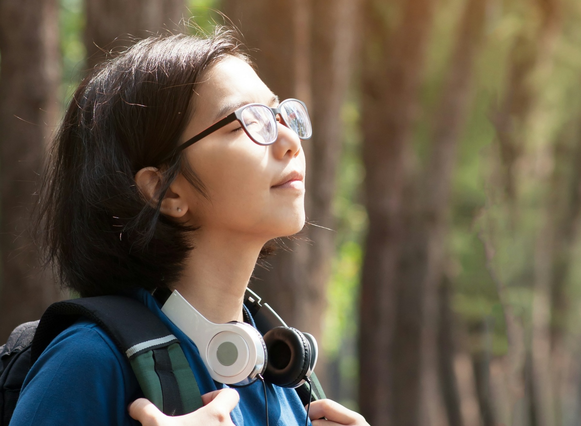 Young woman with headphones in the sunlight (Unsplash)