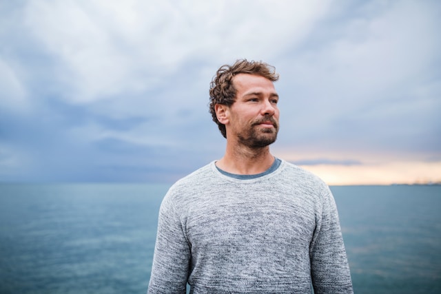 Calm man standing by water (unsplash)