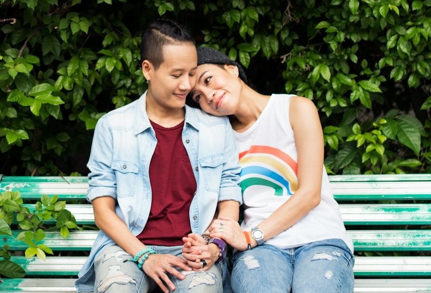 Two women holding hands on a bench (Unsplash)