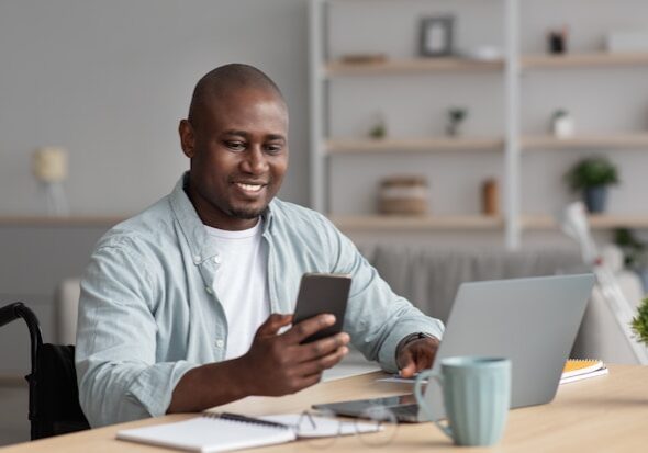 Man in wheelchair holding at desk (Unsplash)